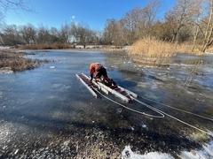Leitern auf Eisfläche und Feuerwehrmann liegend dabei