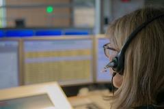 Mitarbeiterin am PC mit Headset und arbeitet.