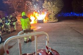 Brennende Autos davor Feuerwehrmänner