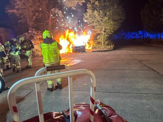 Brennende Autos davor Feuerwehrmänner