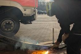 Arbeiten mit dem Plasmaschneider, es sind Funken zu sehen, eine Feuerwehrmann sowie das Fahrzeug sind auch auf dem Bild