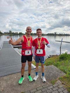 Gruppenbild der zwei am Wasser mit Medaille