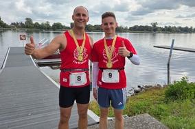 Gruppenbild der zwei am Wasser mit Medaille