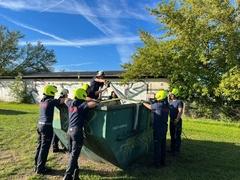 Feuerwehrmänner stehen um einen Container.