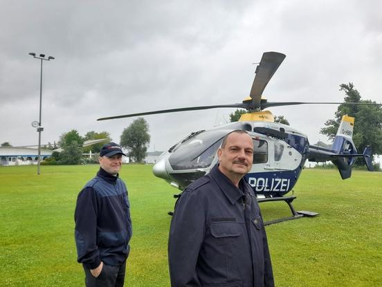 Zwei Männer vor einem Hubschrauber auf der Wiese