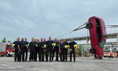Gruppenbild mit einem Auto, welches hochkant steht