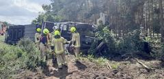 LKW liegt auf Seite, davor Feuerwehrmänner