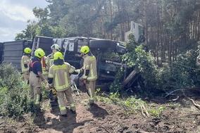 LKW liegt auf Seite, davor Feuerwehrmänner