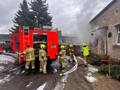 Feuerwehrmänner am Fahrzeug beim Schlauchabwickeln