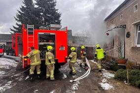 Feuerwehrmänner am Fahrzeug beim Schlauchabwickeln