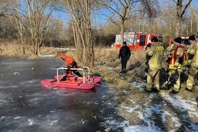 Feuerwehrmänner an Land und der Eisretter auf dem Wasser