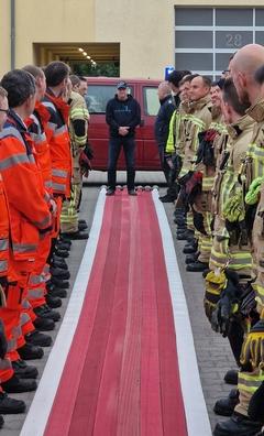 Feuerwehrmänner stehen Spalier. Ein roter Schlauchteppich ist ausgelegt