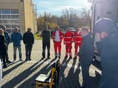 Mitarbeiter stehen draußen am RTW und bekommen die Trage vorgestellt