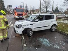 Kaputtes weißes Auto, dahinter ein Feuerwehrfahrzeug