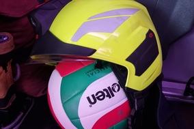 Ein Volleyball hat einen Feuerwehrhelm auf. Beides liegt auf einem Sitz im Auto.