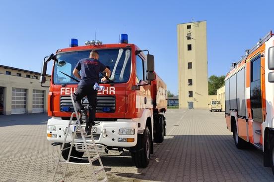 Feuerwehrmann auf Leiter und reinigt die Scheibe eines Fahrzeuges