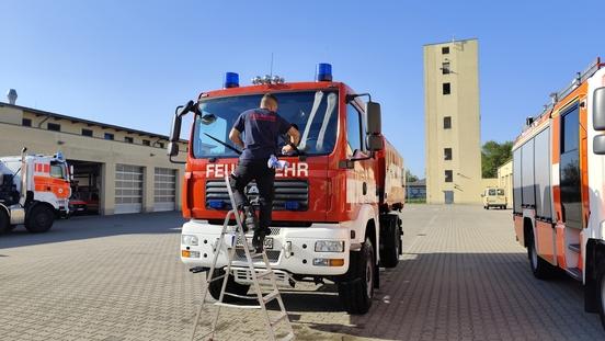 Feuerwehrmann auf Leiter und reinigt die Scheibe eines Fahrzeuges