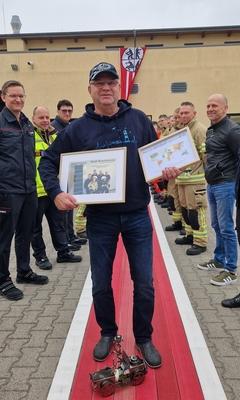 Feuerwehrmann zeigt seine Geschenke. Zwei Bilderrahmen hat er in der Hand