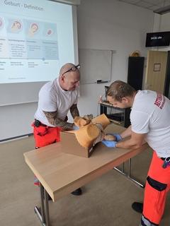 Zwei Rettungskräfte üben am Geburtsphantom