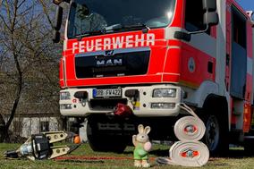 Feuerwehrauto und davor Osterhasenfigur, Schere-Spreizer und ein Schlauch als Hase gewickelt