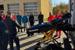 Mitarbeiter stehen draußen am RTW und bekommen die Trage vorgestellt