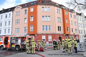 Feuerwehrmänner und ihre Fahrzeuge vor einem Haus.