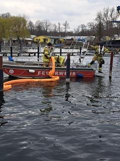 Rettungsboot mit drei Mann und Ölsperren.