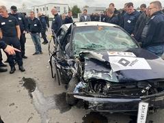 Ein gecrashtes Fahrzeug mit vielen Personen um das Auto.