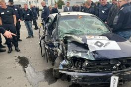 Ein gecrashtes Fahrzeug mit vielen Personen um das Auto.