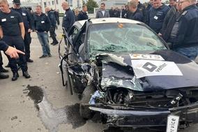 Ein gecrashtes Fahrzeug mit vielen Personen um das Auto.