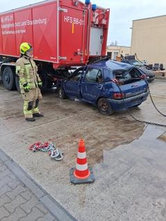 PKW unter Fahrzeug eingeklemmt, davor steht ein Feuerwehrmann