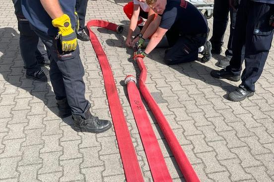 Drei Schläuche werden von Feuerwehrmännern bearbeitet
