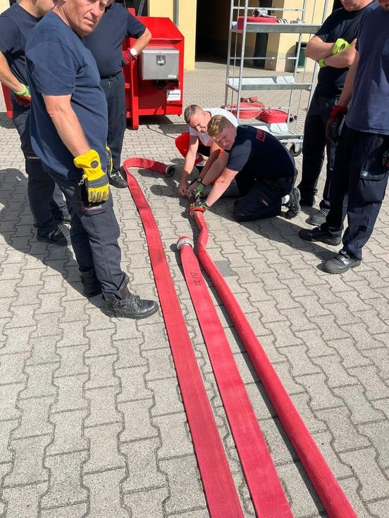 Drei Schläuche werden von Feuerwehrmännern bearbeitet