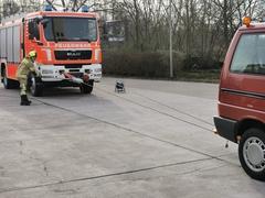 Ein Feuerwehrfahrzeug und ein MTW mit einem Feuerwehrmann. Dazwischen ist ein Seil gespannt