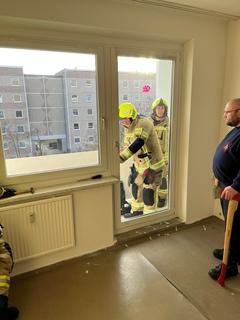 Männer stehen auf dem Balkon. Sie versuchen die Terassentür zu öffnen.