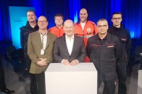 Bundeskanzler Olaf Scholz mit Vertreten der Feuerwehr und dem DRK am Rednerpult