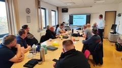 Mitarbeiter von hinten abgebildet, die im Seminarraum sitzen