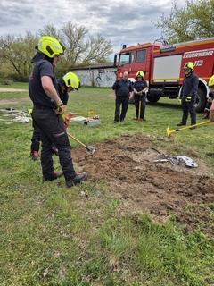 Mehrere Feuerwehrmänner stehen im Halbkreis, dahinter ein Fahrzeug