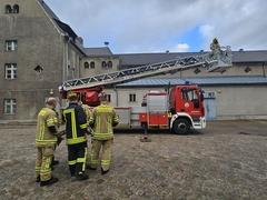 Drehleiter beim ausfahren des Korbes. Davor stehen Feuerwehrmänner