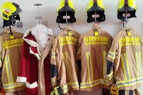 Bild von Einsatzbekleidung am Haken und dazu der Weihnachtsmannmantel