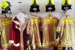 Bild von Einsatzbekleidung am Haken und dazu der Weihnachtsmannmantel