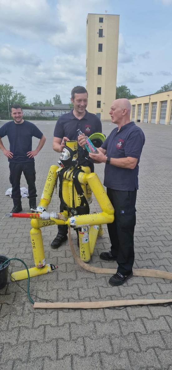 Feuerwehrmänner stehen an Figur aus Pressluftflaschen