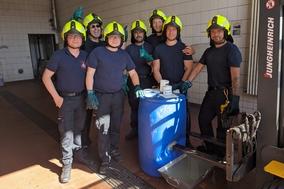 Gruppenbild in der Fahrzeughalle an einer blauen Tonne