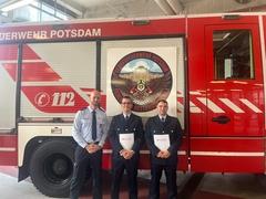 Die zwei Herren und ihr Ausbilder vom einem Feuerwehrfahrzeug