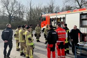 Eine Gruppe von Feuerwehrleuten steht am Fahrzeug