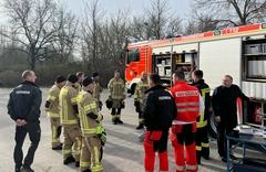 Eine Gruppe von Feuerwehrleuten steht am Fahrzeug