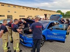 Kameradinnen und Kameraden an einem E-Fahrzeug