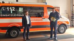 Der Oberbürgermeister und Kollege Rudolph mit Urkunde und Blumen vor dem ELW