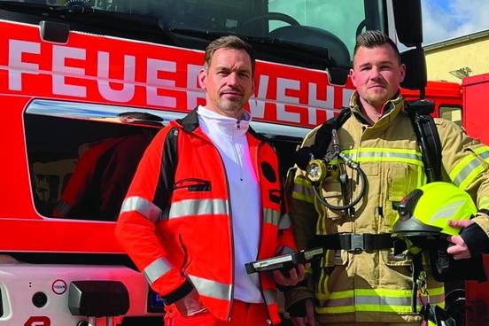 2 Mitarbeiter der Feuerwehr vor einem Fahrzeug