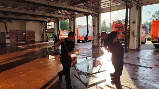 Feuerwehrmänner reinigen den Boden der Fahrzeughalle